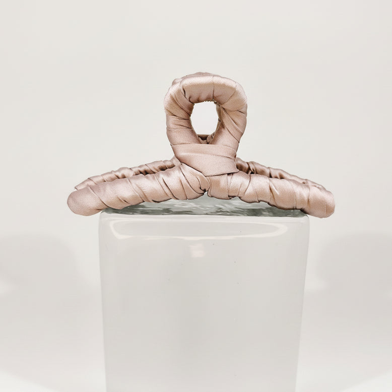 rosé Klammer auf Glasklotz vor weißem Hintergrund