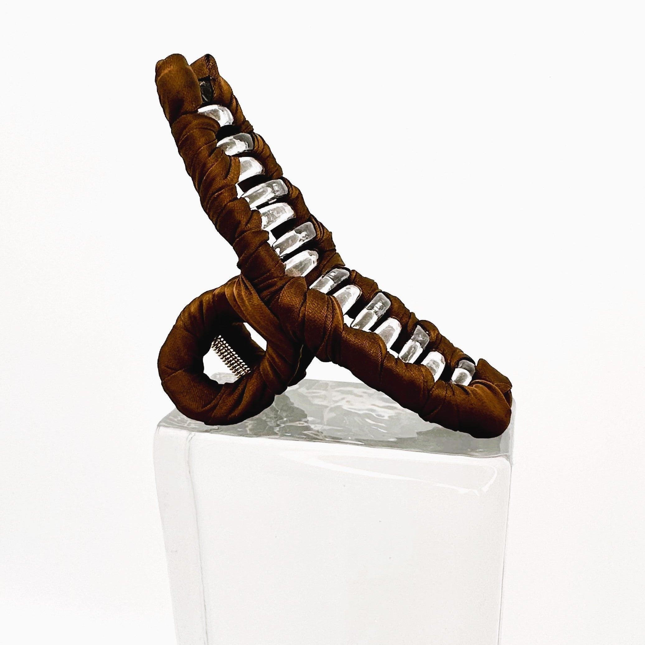 braune Klammer auf Glasklotz vor weißem Hintergrund