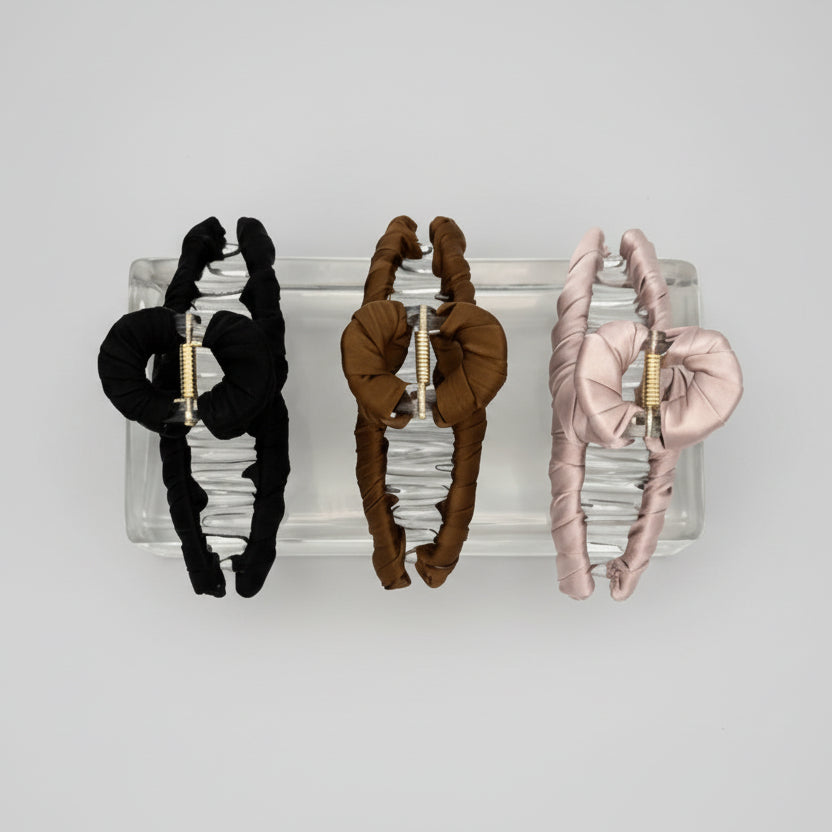 drei Haarklammer aus Satin schwarz braun rosa auf Glasblock