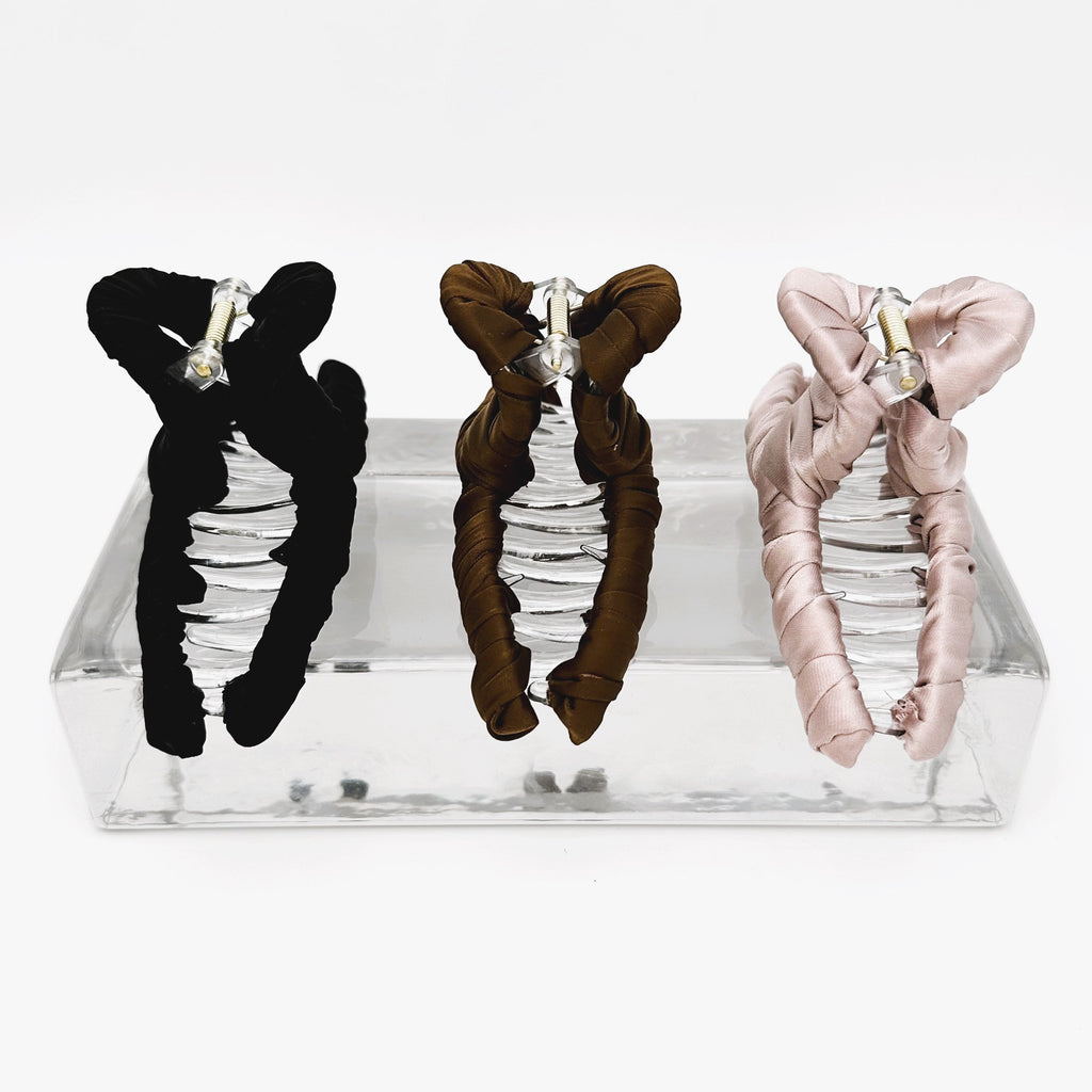 drei Haarklammer aus Satin schwarz braun rosa auf Glasblock